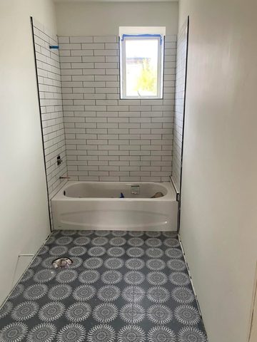 Subway tile tub surround with a patterned tile floor