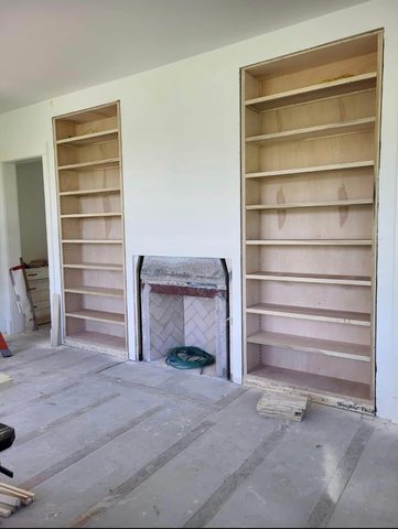 Floor-to-ceiling bookshelves framing a fireplace, before paint