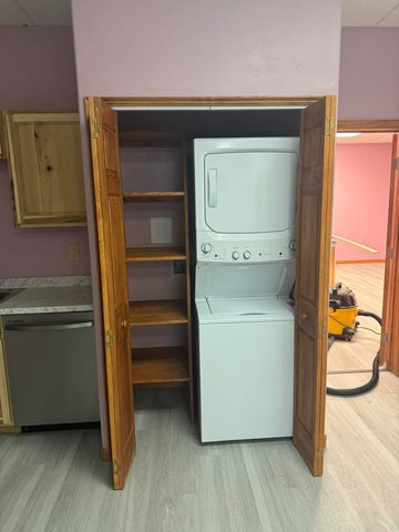 Closet with shelving and a stacked washer and dryer
